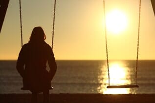 Lonely woman watching sunset alone in swing — Funeral Home in Logan, UT